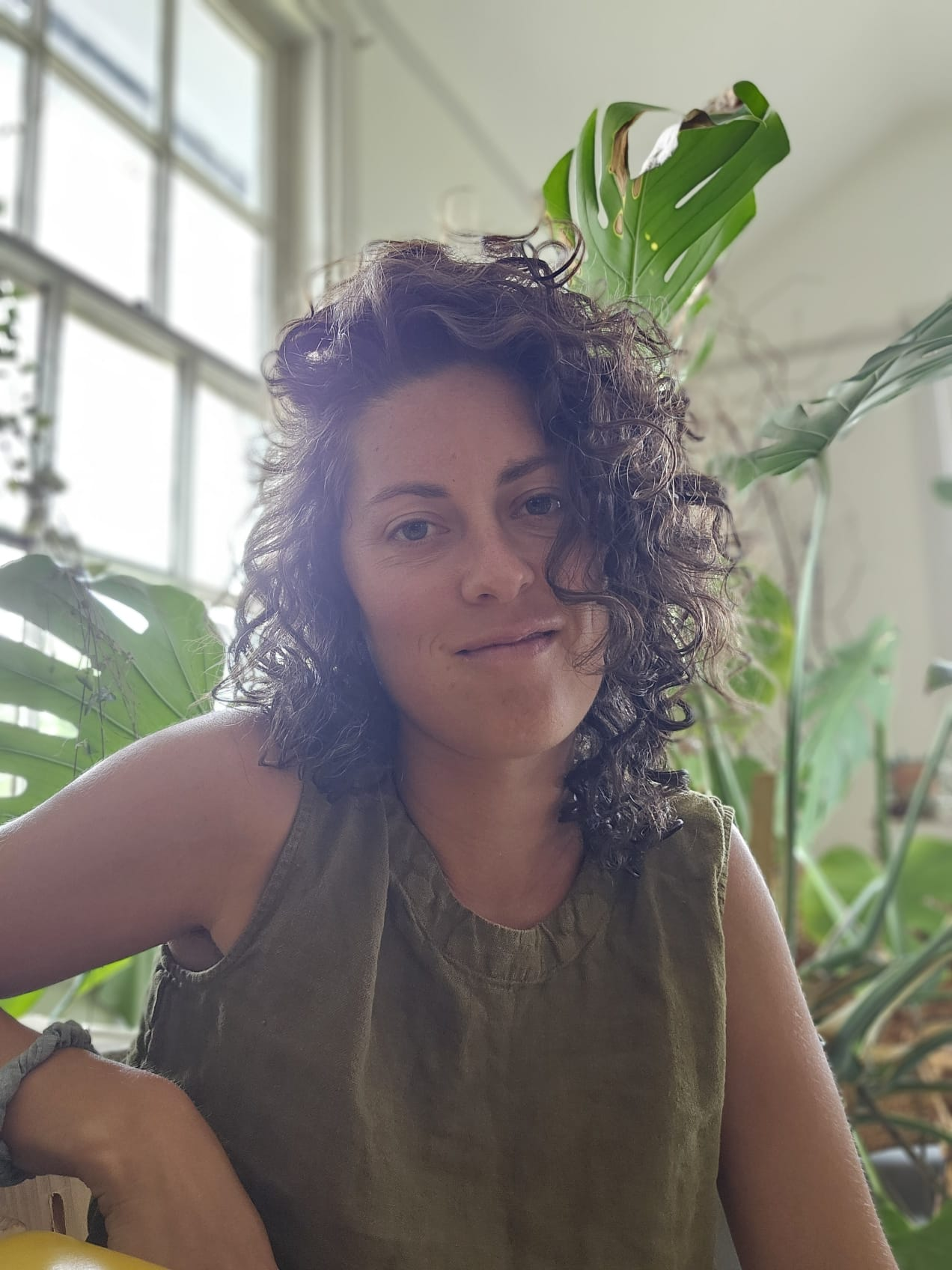 Headshot of Em Chiappinelli with a background of plants behind her.